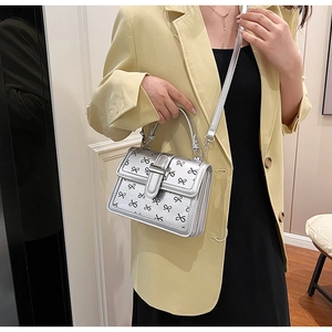 Borsa argentata con stampa a fiocchi neri indossata da modella in giacca gialla