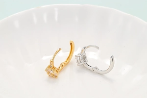 Macro detail of hinged gold and silver heart earrings with micro-pave zirconia stones