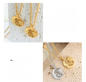 Detail of sun and starburst pendant in gold and silver finish on textured stone