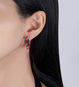 Close-up of dangling earrings with rainbow heart-shaped zircons on a model's ear