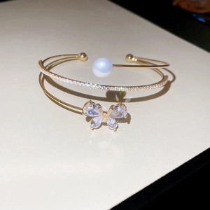 Macro detail of gold flower pearl bangle with sparkling zircon stones and butterfly design