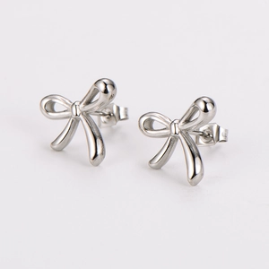 Macro shot of silver bow stud earrings with polished metallic surface on white background