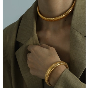 Close-up of gold chunky textured spring collar necklace and matching bracelet on a model
