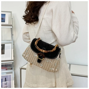 Detail of hand-woven straw bag with floral embroidery and natural bamboo handle