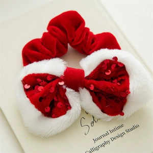 Detail of red velvet Christmas bow scrunchie with white faux fur trim and shiny sequins