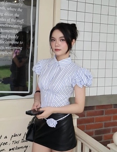 Detail of blue striped puff sleeve polo top paired with a black leather skirt outfit