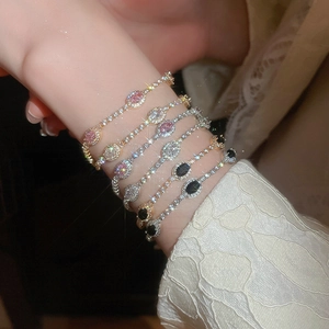 Close-up of stacked gold and silver bracelets featuring oval zircons and starburst charms