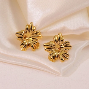 Boucles d'oreilles fleurs dorées polies placées sur un fond de soie beige doux