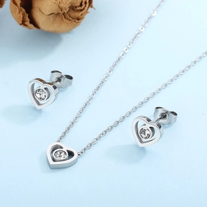 Macro view of silver hollow heart jewelry set with clear zircon on light blue surface