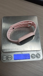 Pink LED sports watch weighing only 18.8g on a digital scale showing its lightweight design