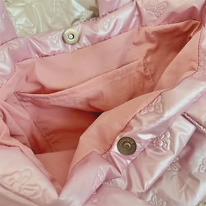 Detail view of pink quilted handbag showing magnetic snap closure and bow texture