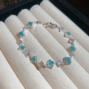Macro shot of silver bracelet with green square stones on velvet jewelry tray