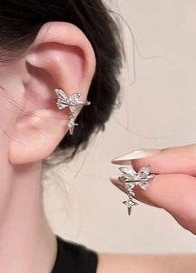 Macro detail of a silver-toned butterfly ear cuff featuring sparkling zircon stones and star drop.