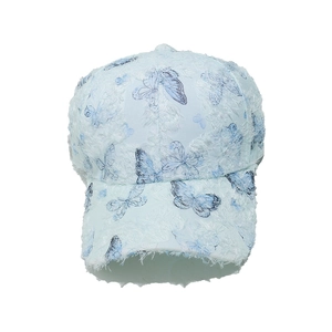 Detail showing blue butterfly patterns and textured fringe fabric on baseball cap