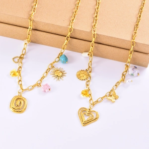 Bohemian gold necklace featuring sun, butterfly, and pink flower charms on a white surface