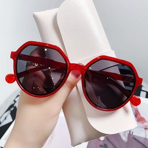 Close-up of red translucent polygon sunglasses with dark lenses and soft leather case