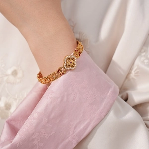 Detail of vintage gold brushed bracelet featuring filigree work with pearls and rubies