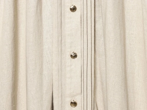 Detail shot of beige linen fabric texture and elegant gold metal buttons on dress