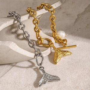 Close-up of gold and silver fishtail bracelets with OT buckle and a white pearl detail