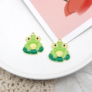 Detail shot of a cute green enamel frog sitting on a leaf pendant with golden edges