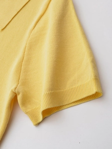 Detail of light yellow knit polo shirt showing ribbed cuffs and premium fabric texture