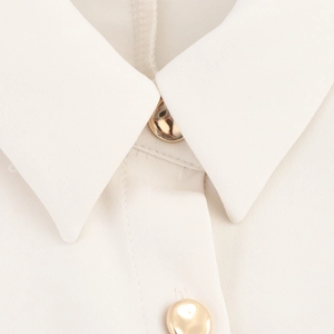 Beige sleeveless dress with padded shoulders, turnover collar, and gold button detail