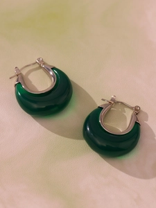 Detail view of dark green resin crescent earrings with polished silver metal hoop clasp