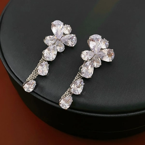 Detail of silver flower earrings featuring shimmering zircon petals and elegant teardrop pendants