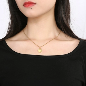 Elegant gold heart locket pendant necklace on model wearing black outfit