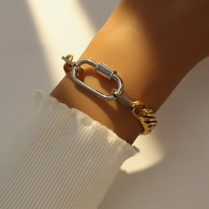 Detailed shot of two-tone gold curb chain bracelet with silver lobster clasp on wrist