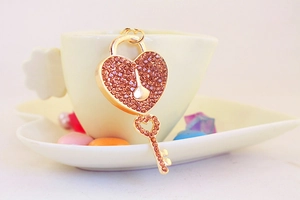 Detail of heart lock and key keychain with pink rhinestones on a yellow plate