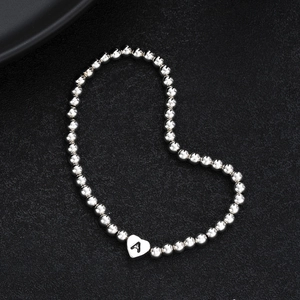Detail of silver beaded heart bracelet featuring a custom letter A engraved charm