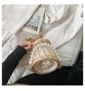 Detail of woven straw bucket bag featuring large pearls and a white drawstring lining