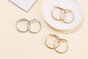 Macro detail of textured hoop earrings in gold, silver and rose gold finishes