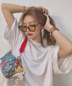 Detail of square black sunglasses with orange lenses on a model wearing a denim logo bag