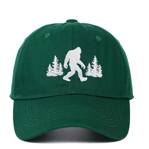Washed dark green cotton baseball cap with white Bigfoot embroidery in pine forest