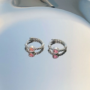 Close-up of silver twist texture hoop earrings featuring a pink heart-shaped stone