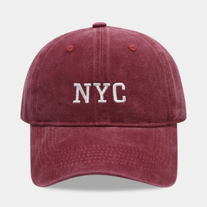 Detailed close-up of white NYC embroidery on vintage burgundy washed cotton baseball cap