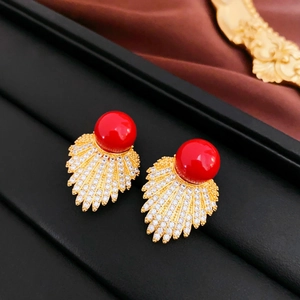 Detailed close-up of fan-shaped leaf earrings with red pearls and zircon inlays
