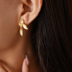 Close-up of elegant gold bow earrings on a model showing metallic crinkle texture
