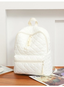 Dettaglio zaino trapuntato bianco che mostra motivi a rombi e trama della zip in nylon
