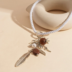 Detail of bohemian necklace featuring metal feathers, wood beads, and faux pearl charms