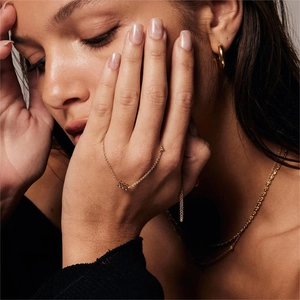 Close-up of a gold 555 number ring worn by a model with matching gold jewelry set