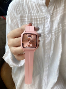 Detail of pink silicone strap and square rose gold watch face on model's wrist