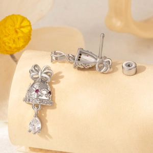 Silver bell earrings with red crystals and pear-cut drop stones on floral background