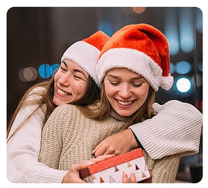 Women wearing glowing red plush Christmas hats and sharing a holiday gift box
