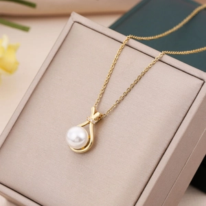 Elegant gold pearl necklace with zircon-studded pendant on a beige jewelry box surface