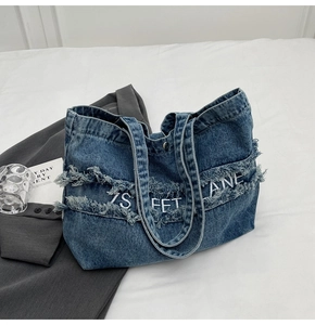 Vue détaillée du sac en jean montrant les bords effilochés et la broderie blanche chic