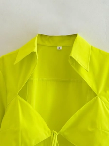 Gros plan d'un col de chemise jaune fluo avec étiquette de taille S sur fond blanc