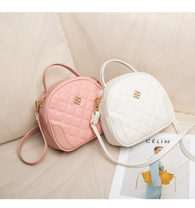 Pink and white quilted handbags with gold clover hardware on soft beige background